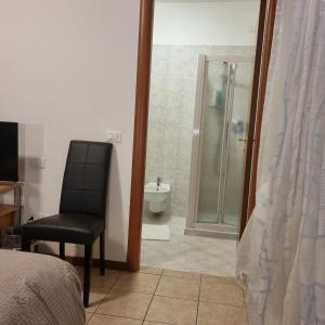 a bedroom with a bathroom with a shower and a chair at Laguna B&B in Quarto dʼAltino