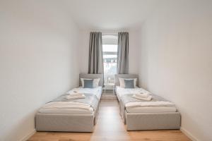 two beds in a room with a window at BENVILLE Meißen - WLAN - Smart-TV - Free Parking in Meißen