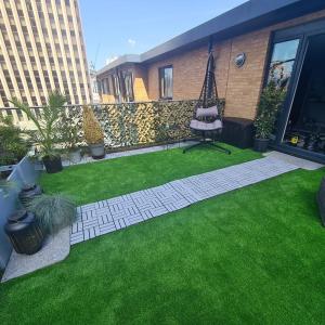 a backyard with green grass and a walkway at Luxury 9ine PENTHOUSE WITH GARDEN & JACUZZI in Birmingham