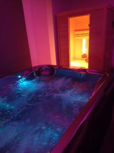 jacuzzi en una habitación con luces púrpuras en Paradis Secret Spa, en Damprichard