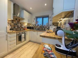 a kitchen with white cabinets and a wooden floor at Lake District romantic get away in 1 acre gardens off M6 in Penrith