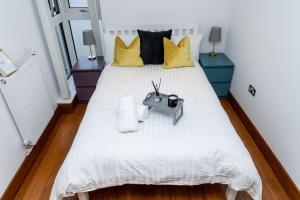 1 dormitorio con 1 cama blanca grande con almohadas amarillas en Luxury 2 bed- 2 bath Riverside Haven, en Londres