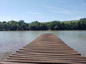 a wooden dock in the middle of a lake at Casa rústica às margens do lago 