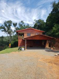 a small red house with a large driveway at Casa rústica às margens do lago 