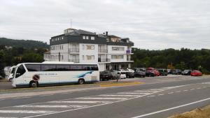 a white bus parked in front of a building at Hotel Conde in Taboadela