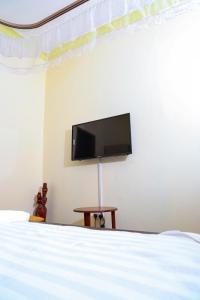 1 dormitorio con TV de pantalla plana en la pared en Crown Inn Bulindo, en Wakiso