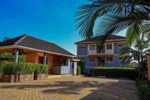 ein blaues Haus mit einer Palme davor in der Unterkunft Crown Inn Bulindo in Wakiso
