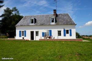 una casa blanca con persianas azules en un patio en JenFyz Gîte avec jacuzzi à la campagne, en Conteville