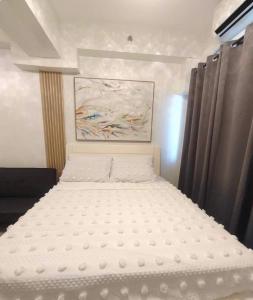 a white bed in a bedroom with a painting at Condotel-Shore 2 Residences MOA in Manila