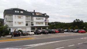a parking lot with cars parked in front of a building at Hotel Conde in Taboadela
