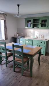 a kitchen with green cabinets and a table and chairs at Dom Šumiac - prízemie in Šumiac