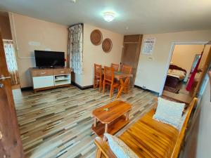 a living room with a television and a table and chairs at Silver Spruce 2BHK Entire Floor Kotagiri in Kotagiri