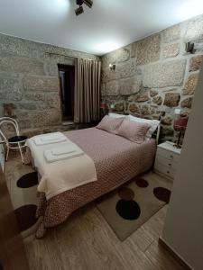 um quarto com uma cama e uma parede de pedra em Casa dos Avós em Avelal