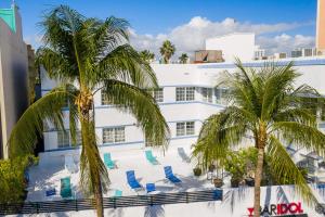 a white building with blue chairs and palm trees at Best location in SOBE - 2 min to beach & Ocean Dr in Miami Beach