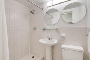 a white bathroom with a sink and a mirror at Best location in SOBE - 2 min to beach & Ocean Dr in Miami Beach