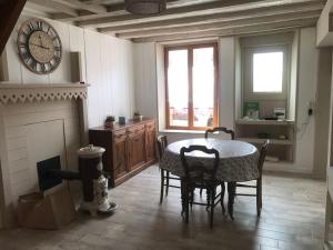 ein Wohnzimmer mit einem Tisch, Stühlen und einer Uhr in der Unterkunft Maison de village cosy avec jardin 