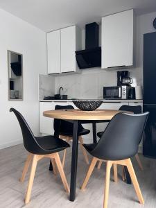 uma cozinha com uma mesa de madeira e cadeiras pretas em Apartament Kropla Bałtyku 18E/6 Darłowo em Darłowo