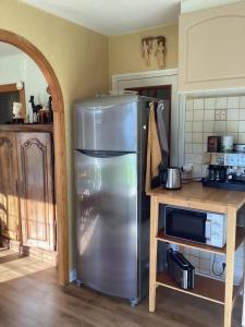 eine Küche mit einem Kühlschrank aus Edelstahl und einer Mikrowelle in der Unterkunft TY Lavarion in Le Bono