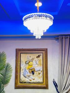 una pintura en una pared con una lámpara de araña en Viceroy Royal Hotel Apartment Islamabad en Islamabad