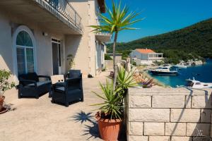 een patio met stoelen en een palmboom naast een gebouw bij Charming Holiday Home Lady Kate in Lastovo