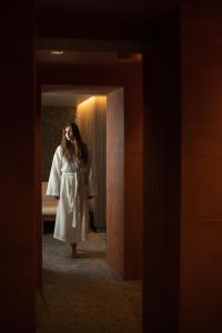 a woman in a white robe standing in a hallway at Narva Hotell & Spaa in Narva
