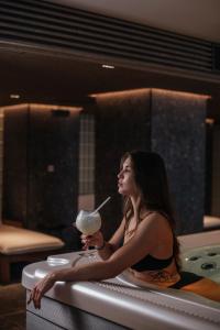 una mujer sentada en una bañera sosteniendo una bebida en Narva Hotell & Spaa, en Narva