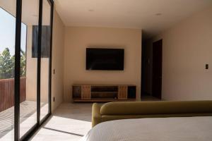 a bedroom with a couch and a television on the wall at Casa Amelia Puerto Escondido in Puerto Escondido