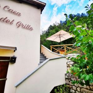 a white building with an umbrella next to stairs at LA CASA DEL GRILLO - Valle del Menotre - Rasiglia in Orsano