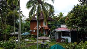 a house with a palm tree in the yard at Garggi Kumarakom Village Homestay in Kumarakom