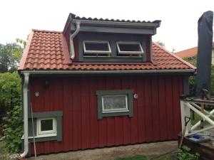 a red house with two windows and a roof at Lilla Gäststugan in Uppsala