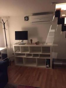 una sala de estar con un monitor de ordenador en un estante en Lilla Gäststugan en Uppsala