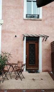 a pink building with two chairs and a door at Aux portes de Lyon in Saint-Fons