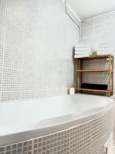 y baño con bañera blanca y azulejos blancos. en Maison cocooning près de Honfleur, en La Rivière-Saint-Sauveur