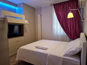a bedroom with a bed with a purple curtain and a tv at Desenzano Luxury Apartment in Desenzano del Garda