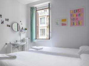 A Room In The City Hostel في سان سيباستيان: غرفة بيضاء بسريرين ومغسلة