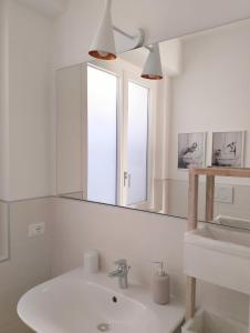 een witte badkamer met een wastafel en een spiegel bij Casa L'agrumeto in Ventimiglia