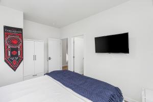 a white bedroom with a bed and a flat screen tv at Dreamfyre's Ancient Dragon Horn Sweet Suite in Seattle