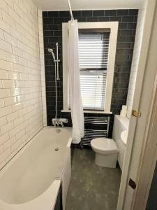 ein Badezimmer mit einer weißen Badewanne und einem WC in der Unterkunft Stylish, Modern & refurbished flat, 1.5m beach in Southend-on-Sea
