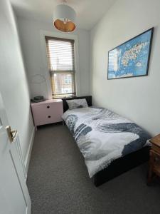 a bedroom with a bed and a dresser and a window at Stylish, Modern & refurbished flat, 1.5m beach in Southend-on-Sea