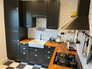 a kitchen with black cabinets and a sink at Stylish, Modern & refurbished flat, 1.5m beach in Southend-on-Sea