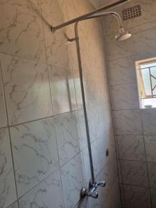 um chuveiro na casa de banho com azulejos de mármore branco em Town Centre Apartment em Livingstone