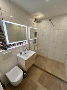 a white bathroom with a toilet and a sink at Lilis Apartment mit Balkon in Augsburg