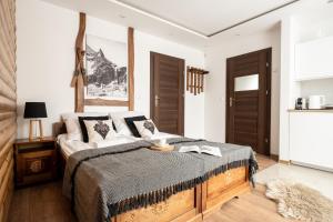 a bedroom with a large bed and a kitchen at Villa Odskocznia Apartamenty Zakopane in Zakopane