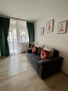 ein Wohnzimmer mit einem Sofa und grünen Vorhängen in der Unterkunft Lilis Apartment mit Balkon in Augsburg