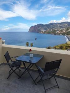 uma mesa e duas cadeiras numa varanda com o oceano em Penthouse Formosa Sunset and Beach em Funchal