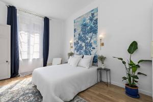 una camera da letto con un grande letto bianco e una pianta in vaso di Appartement cosy Rouen Rive droite a Rouen