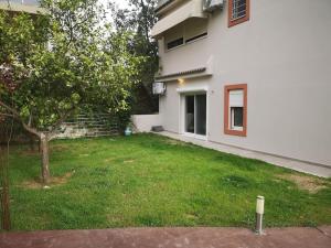 un patio frente a una casa blanca con un árbol en Ground floor apt. with garden, Timfristou 86 Chalandri en Atenas