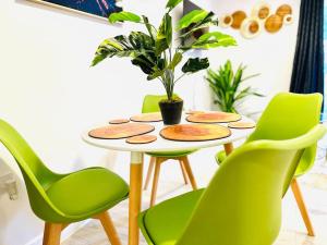 a table with green chairs and a potted plant at Stylish Dover Apt With Castle View in Kent