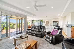 a living room with leather furniture and a kitchen at RidgeRaj - Kerikeri Holiday Home in Kerikeri