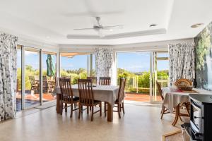 a dining room with a table and chairs and a balcony at RidgeRaj - Kerikeri Holiday Home in Kerikeri